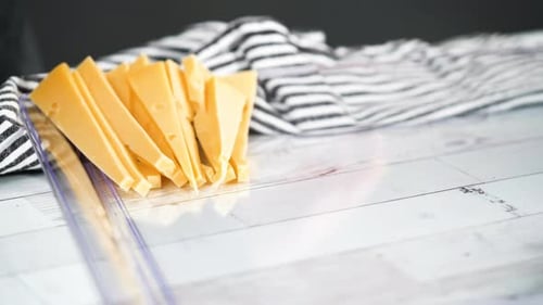 Step by step. Slicing a gourmet cheese on a white cutting board with a kitchen knife.