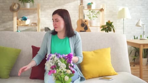 Jeune femme allergique assise dans un appartement moderne, elle éternue et porte un respirateur
