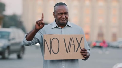 Man Holding Sign Protesting on Urban Street