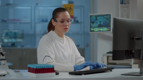 Female Scientist Typing at Computer in Bright Laboratory