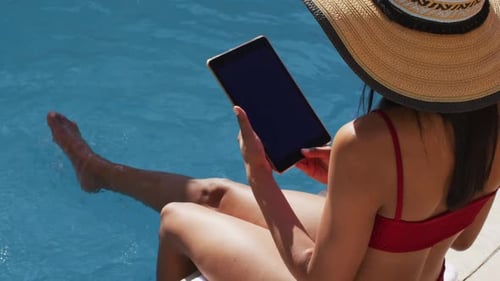 Mixed race woman sitting by a pool at home