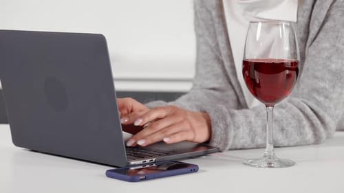 Woman Typing on Laptop with Glass of Wine