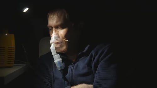 un jeune bel homme inhale avec un nébuliseur