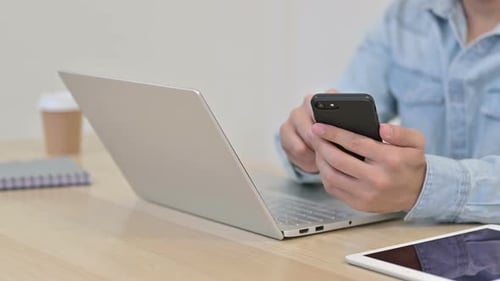 Uso de teléfonos inteligentes por hombre con computadora portátil de cerca