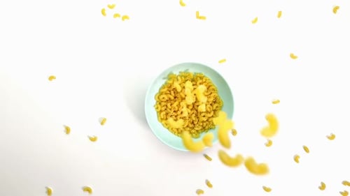 Macaroni Falls on a Blue Plate Top View. Close-up, Slow-motion