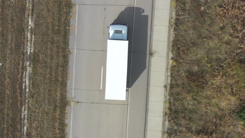 Aerial View of Truck with Trailer Driving on Straight Road and Transporting Goods. Flying Over