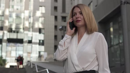 Business woman talking on the phone with employees outdoors near the business center.