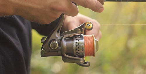 Man Adjusting Fishing Reel on Lake