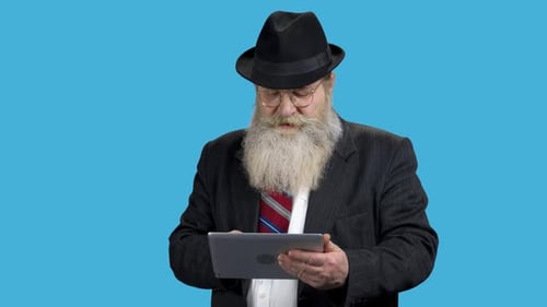 Senior Man Uses Tablet Against Blue Backdrop
