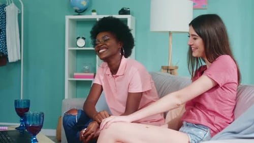 Two Young Women Chatting and Laughing on Sofa