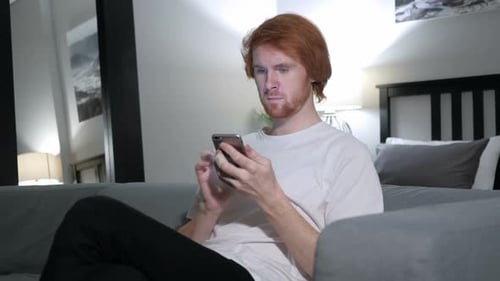Redhead Man Browsing on Smartphone Using Internet
