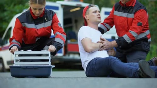 Les ambulanciers paramédicaux font une injection masculine ressentant une douleur thoracique et sont couchés sur la route