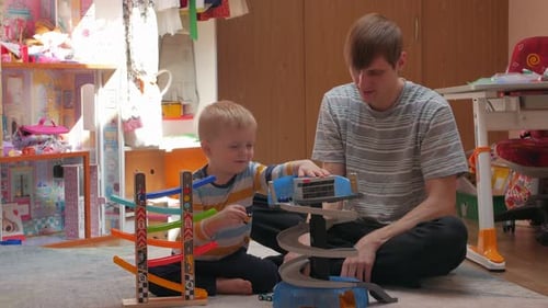 Father and Son Play with Toy Cars Indoors