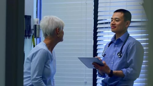 Young Asian male doctor and senior patient interacting with each other at clinic 4k