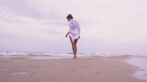 Girl Walks on the Beach on the Background of the Sea