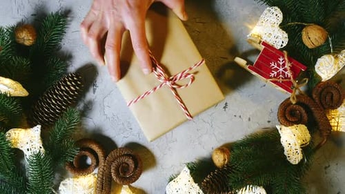 Hand Places Christmas Gift on Decorated Table