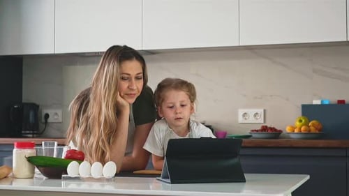 Mother and Child Watching Tablet in Kitchen