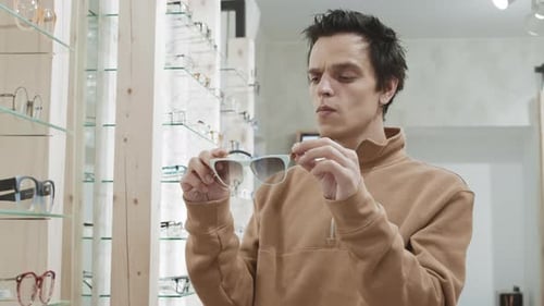 Black-haired Man Choosing Sunglasses in Optician Shop