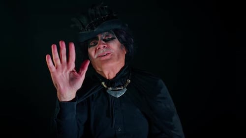 Homem sênior assustador com ondas de maquiagem de bruxo de Halloween na palma da mão em Hello Hi Gesture dá as boas-vindas