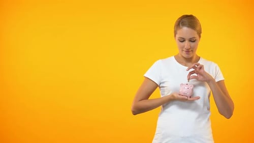 Positive Frau legt Münze ins Sparschwein, Planungsbudget, finanzielle Einsparungen
