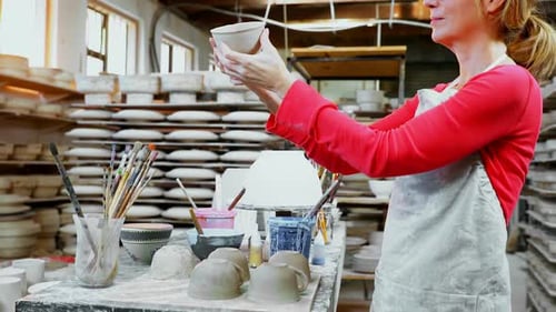 Potter Inspecting Ceramic Bowl in Studio