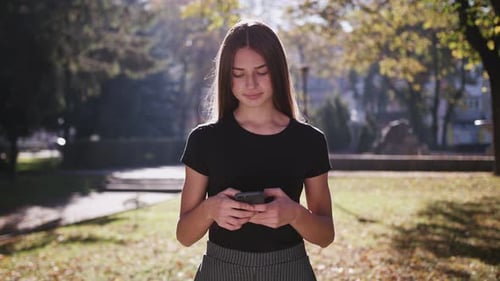 An Attractive Young Lady Using a Phone in Town. Medium Shot
