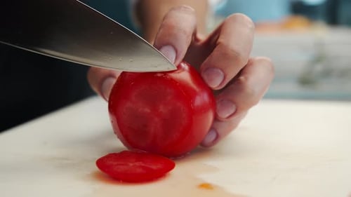 Professional restaurant kitchen, close-up: Chef cuts tomatoes with a knife