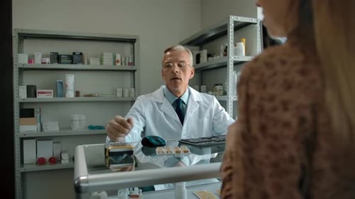 Caucasian Woman is Buying Pills at the Pharmacy Paying with Credit Card