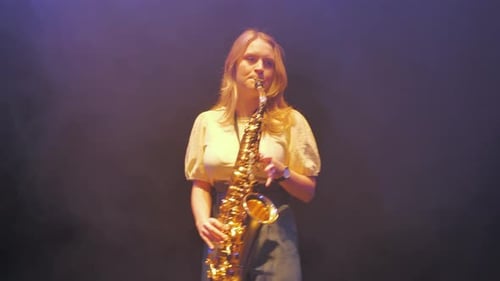 Woman Playing Saxophone on a Dimly Lit Stage