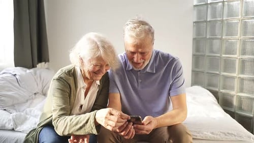 Senior Couple Enjoying Smartphone Together Indoors