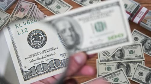 One Hundred Dollars Inspecting Under Magnifying Glass on Money Background