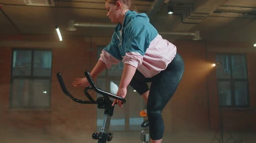 Woman Performs Aerobic Endurance Training Workout Cardio Routine on the Simulators Cycle Training