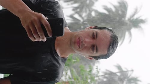 Young Adult in Heavy Rain Using Cellphone