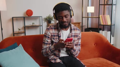 Man Listens to Music on Phone with Headphones
