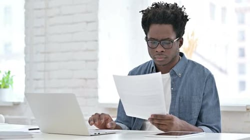 Young Adult Works at Laptop in Modern Office