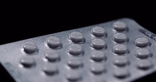 Blister mit medizinischen Pillen auf schwarzem Hintergrund