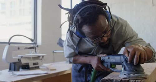 Adult Sanding Wood in Bright Workshop