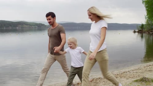 Family Walking by the Lake and Having Fun