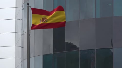 Realistic Spanish Flag Waving in Front of Modern Building