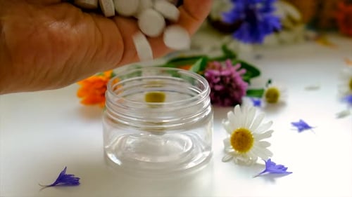 Hand Pours White Tablets into Clear Jar
