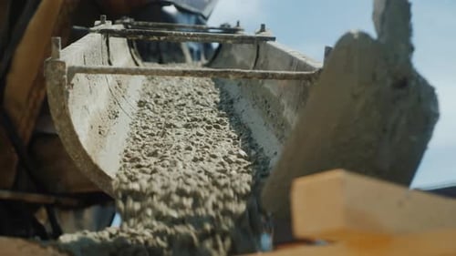 Construire un chalet. Les travailleurs prennent le béton d'un malaxeur dans un coffrage en bois