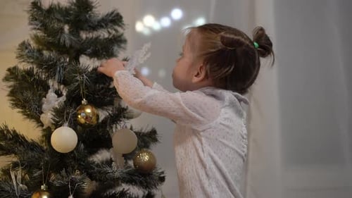 Cute Child Decorating Christmas Tree with Snowflake Ornament