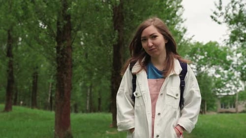Belle femme sourit en marchant le long d'un chemin entouré de feuillage et d'arbres
