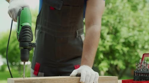 Close Up Hand of Carpenter Drills Wood a Hole with an Electrical Drill