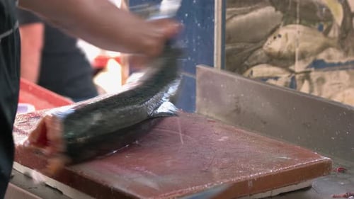 Männliche Hände schneiden einem Fischkopf ab