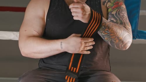 Muscular Man Wraps Wrists with Elastic Bandage