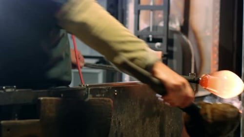Glass Blower Shaping Molten Glass in Workshop