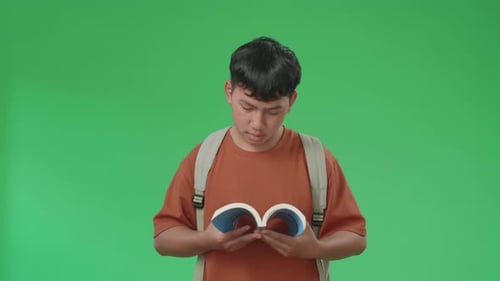 The Front View Of Asian Boy Student Reading A Book While Walking On Green Screen