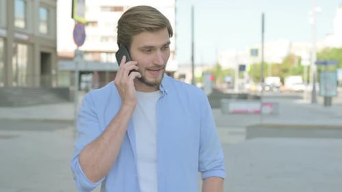 Man Answering Mobile Phone on City Street