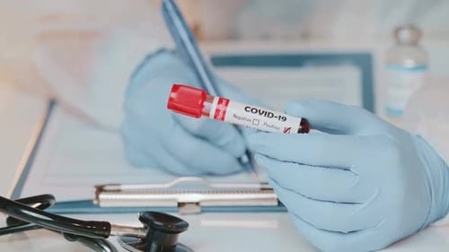 Close Up of Doctors Hand Holding Tube with Positive Blood Test for COVID-19